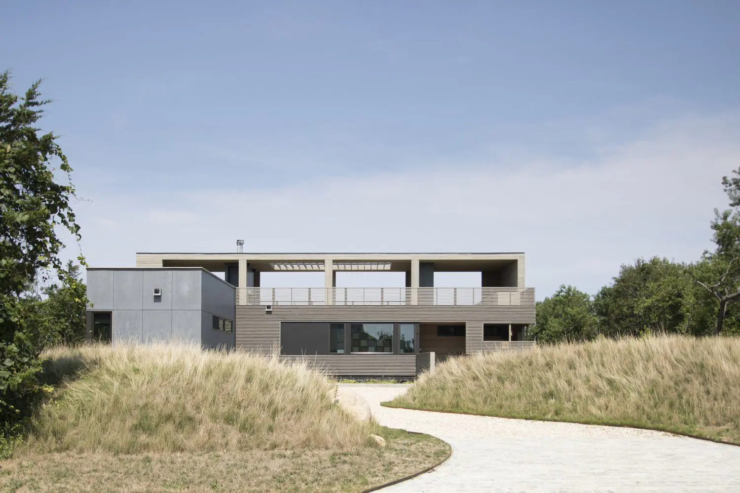 Modern house with flat roof and large windows in a grassy area.