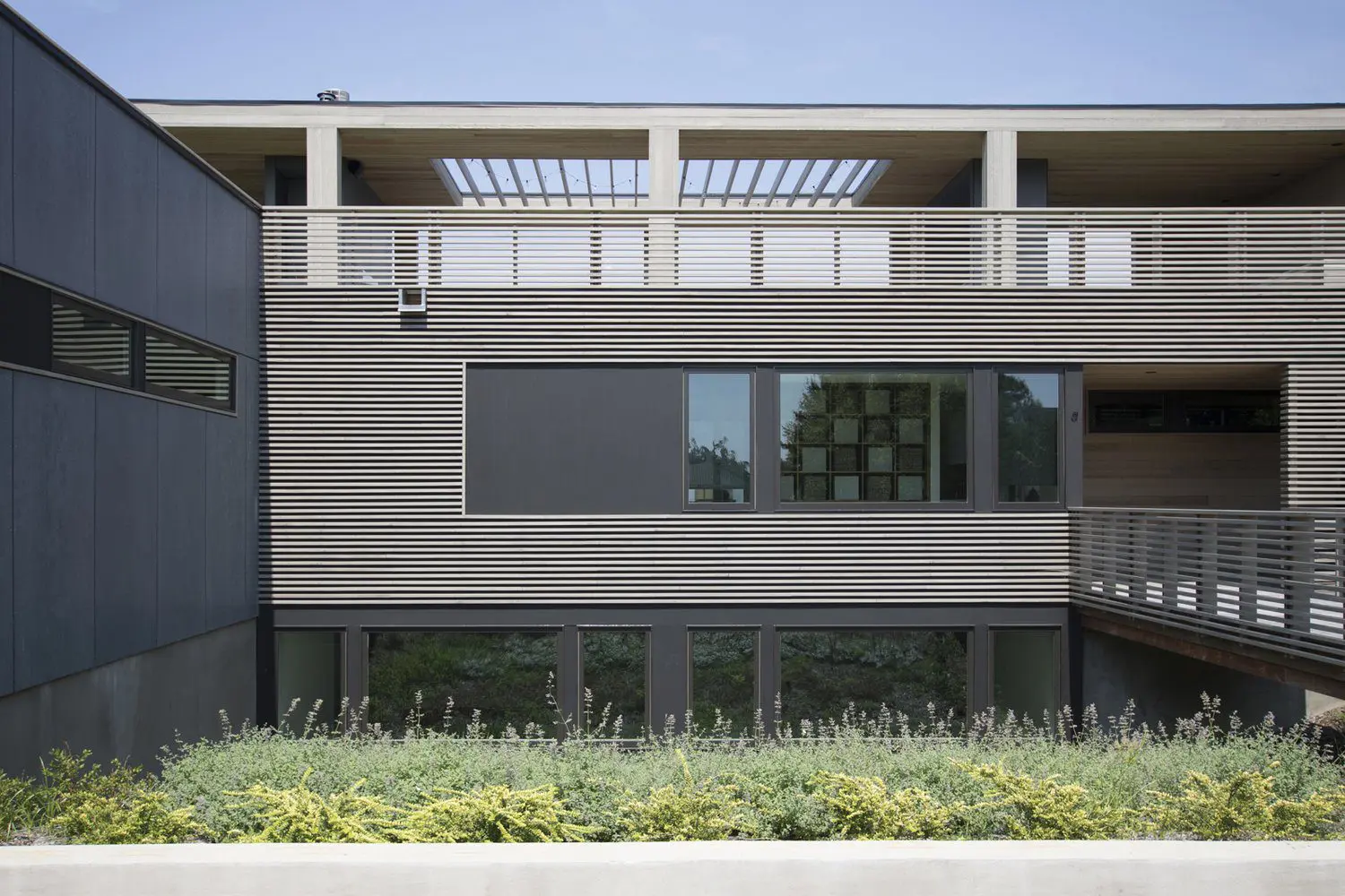 Modern building with wooden siding and large windows under a clear sky.