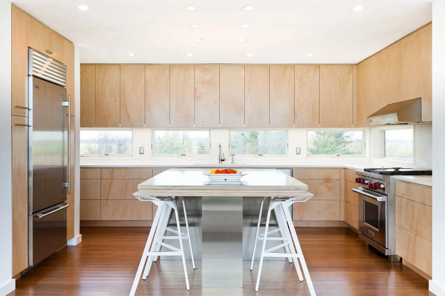 Bright minimalist kitchen with wooden accents and white stools.