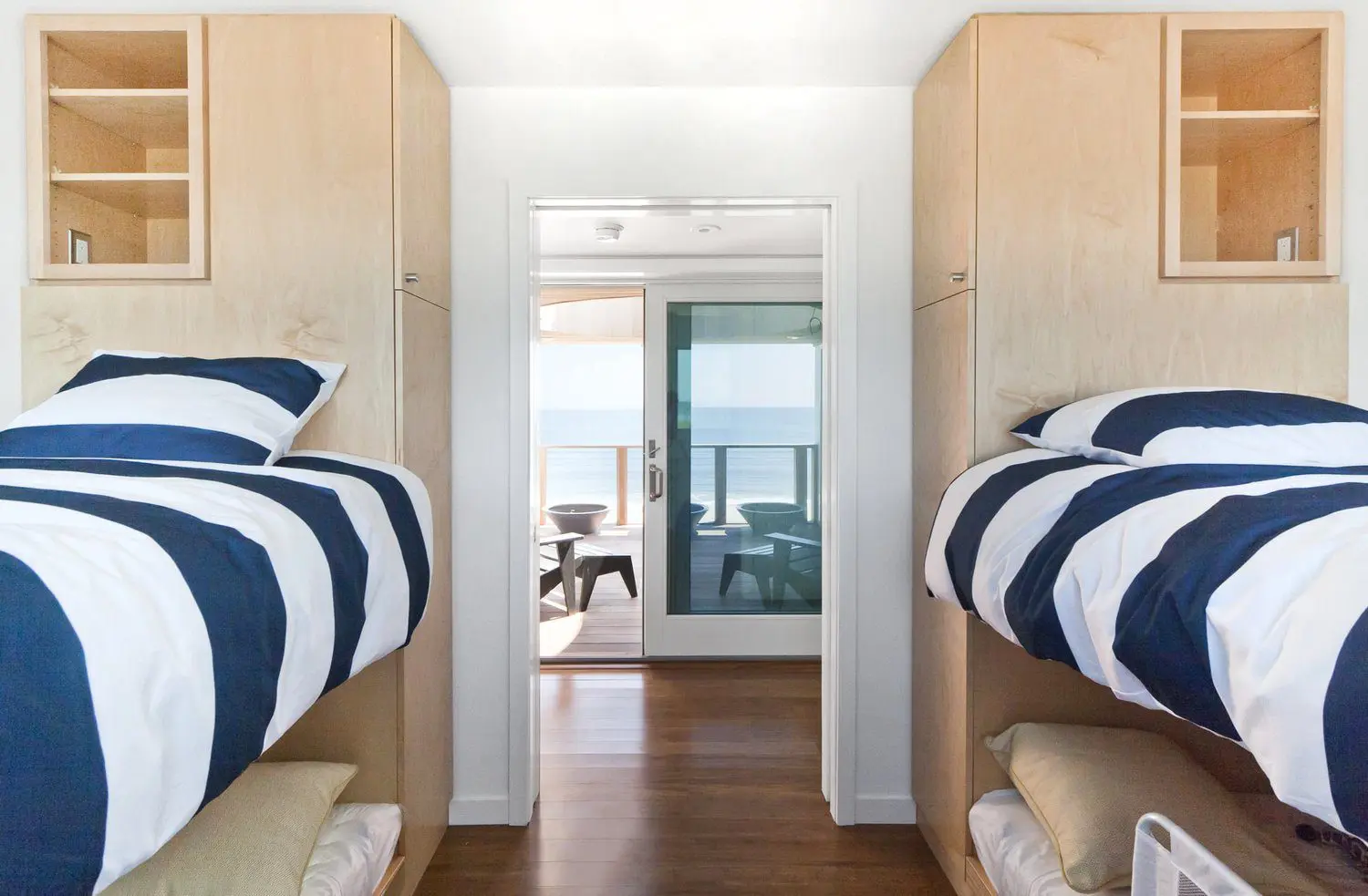 Modern bedroom with twin beds and a view of the living room and balcony.