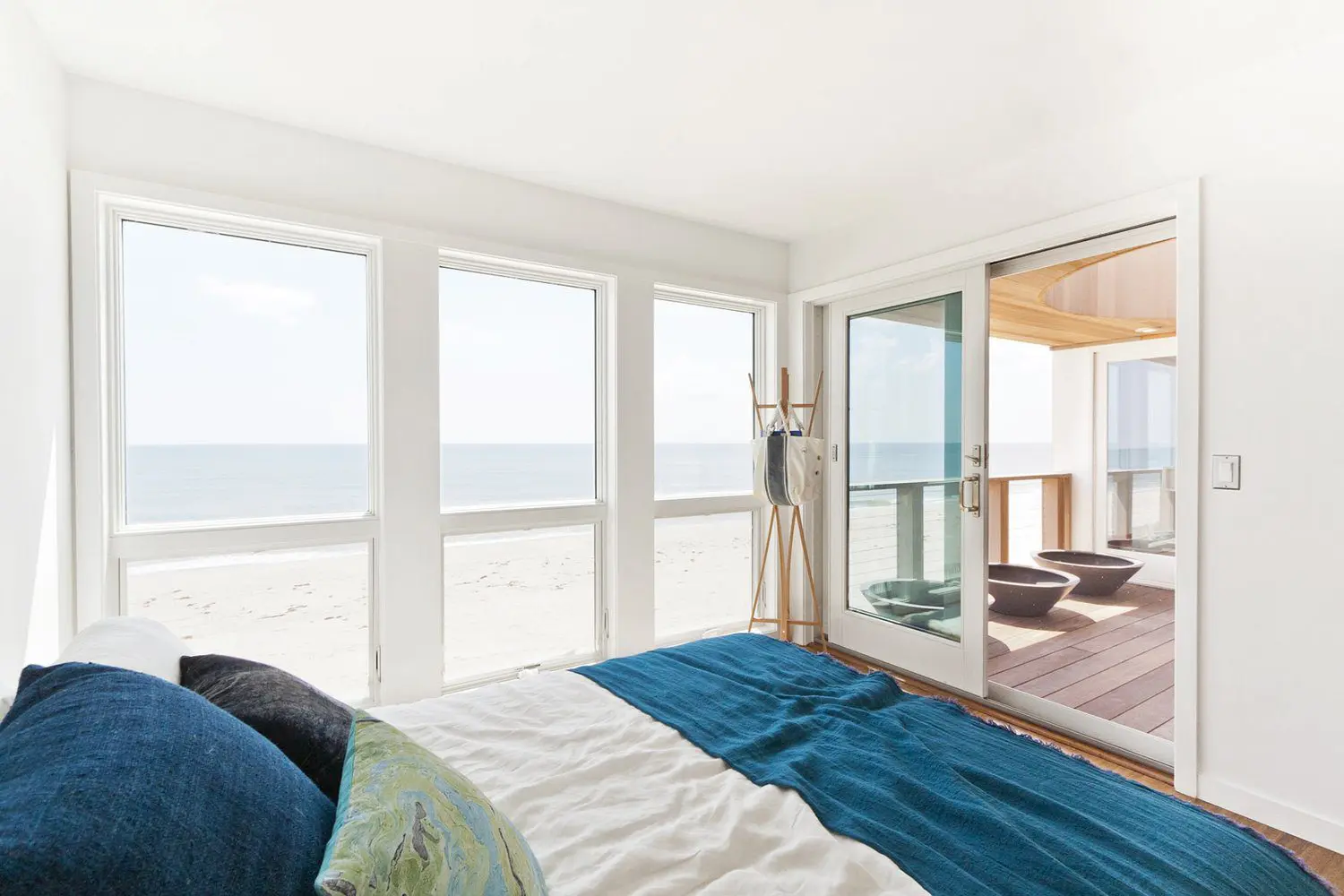 Modern bedroom with large windows overlooking the beach and ocean.