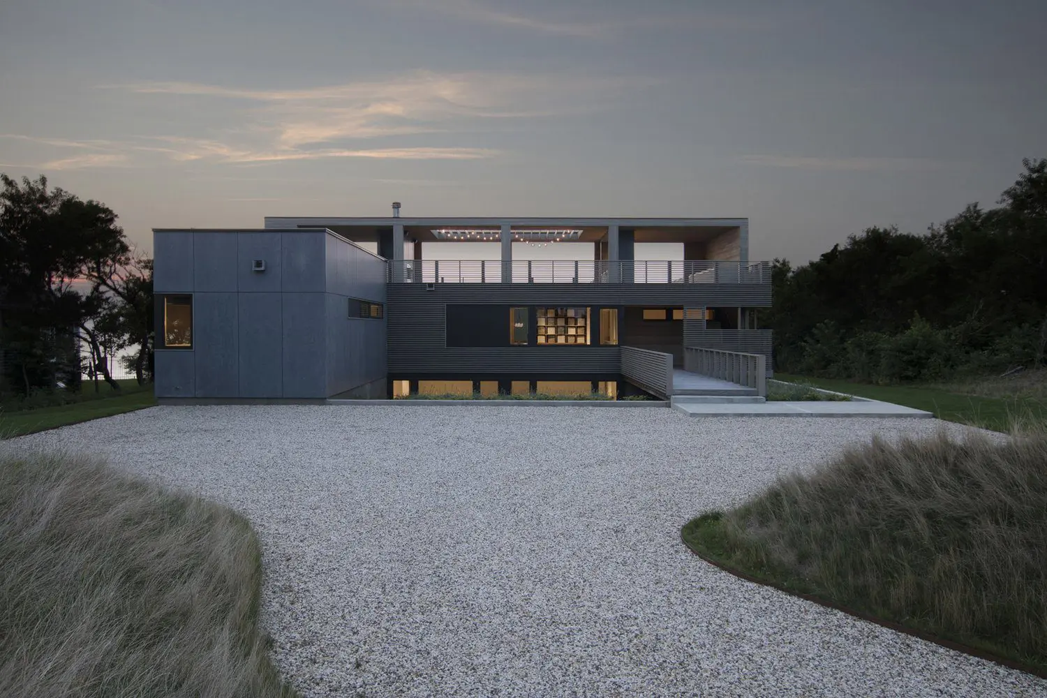 Modern minimalist house with flat roof and large windows at dusk.