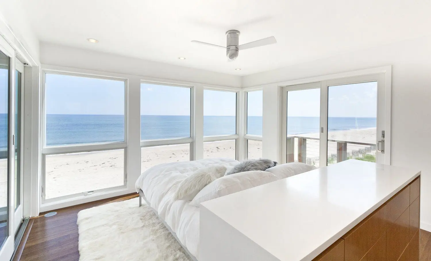 Bright bedroom with large windows overlooking the ocean and beach.