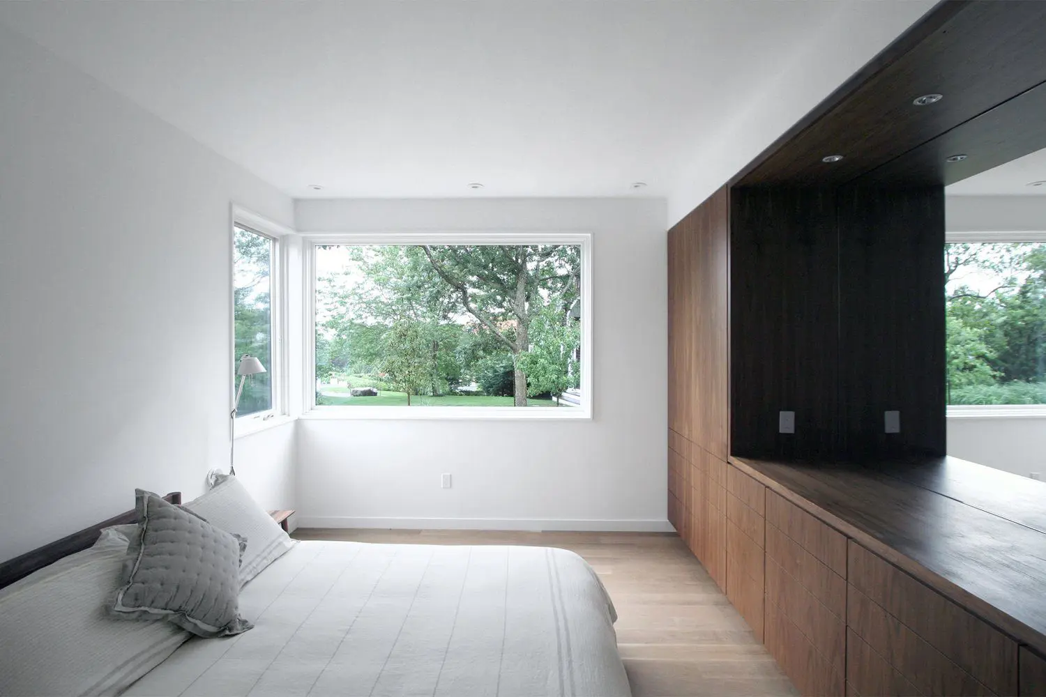 Minimalist bedroom with large window showing greenery outside.