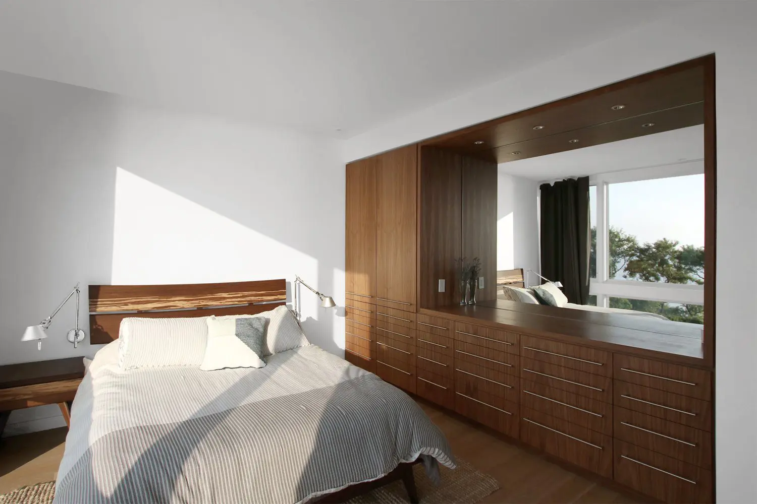 Sunlit bedroom with wooden wardrobe and neutral bedding.