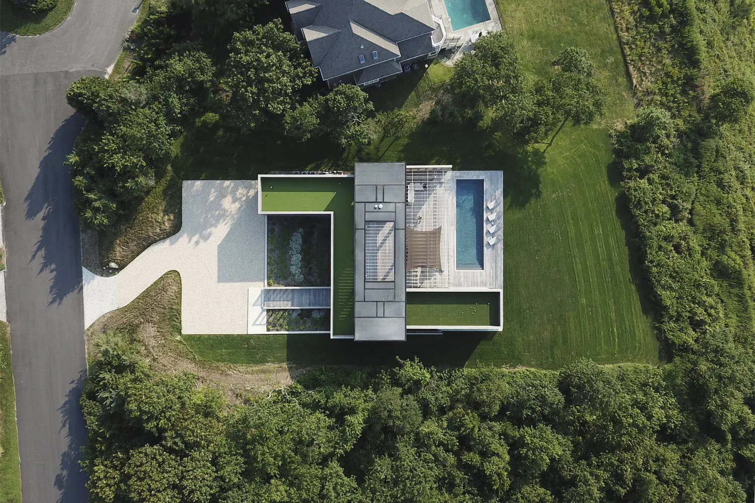 A modern house with a pool, surrounded by greenery.