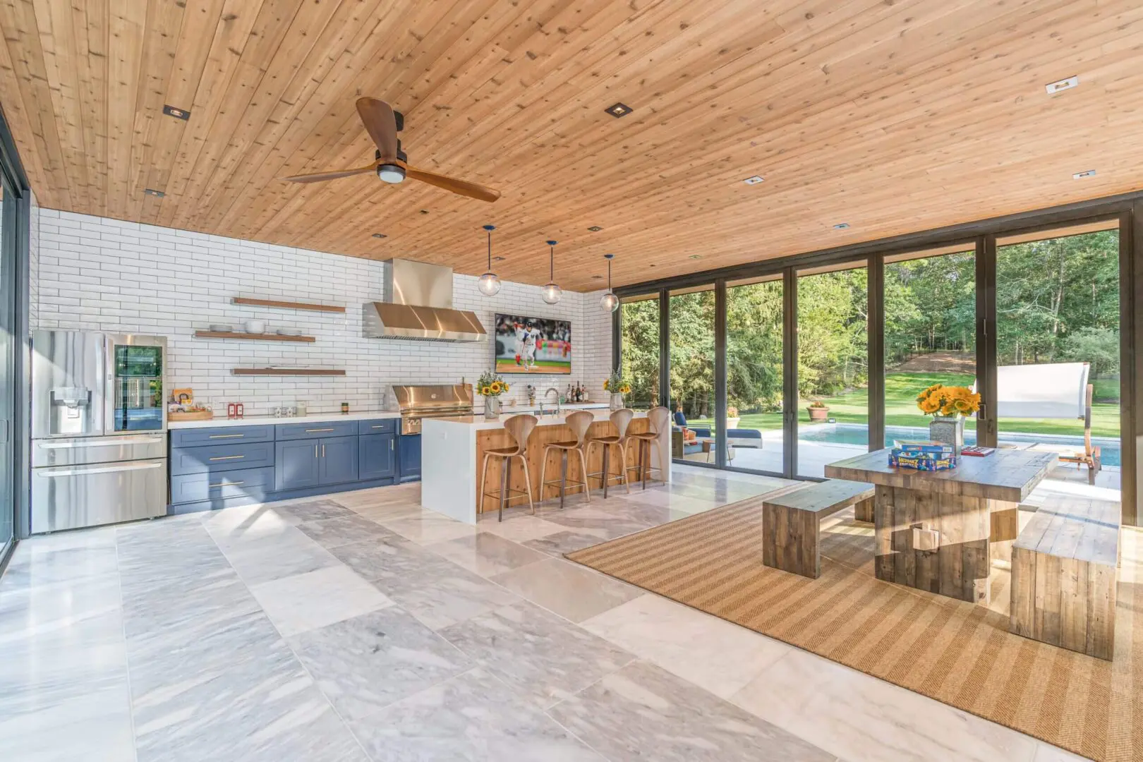 Modern kitchen with wood ceiling and large glass doors opening to a garden.
