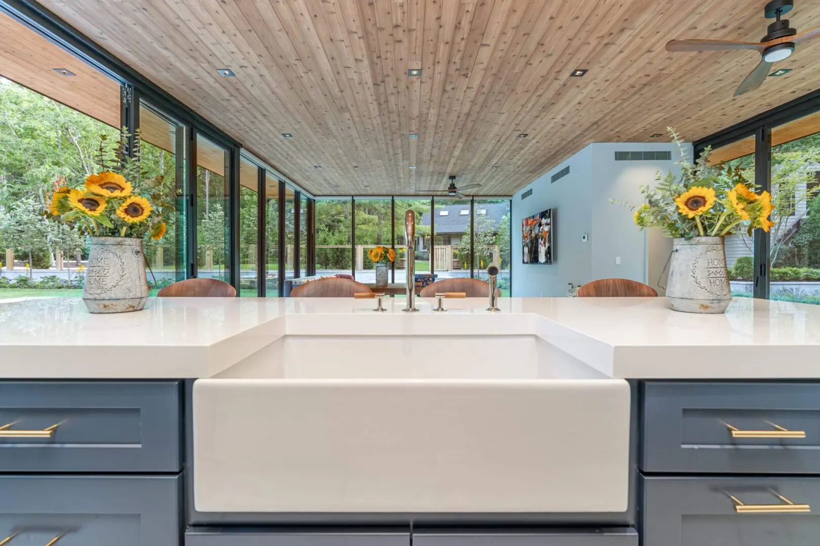Modern kitchen with large farmhouse sink and glass wall views.