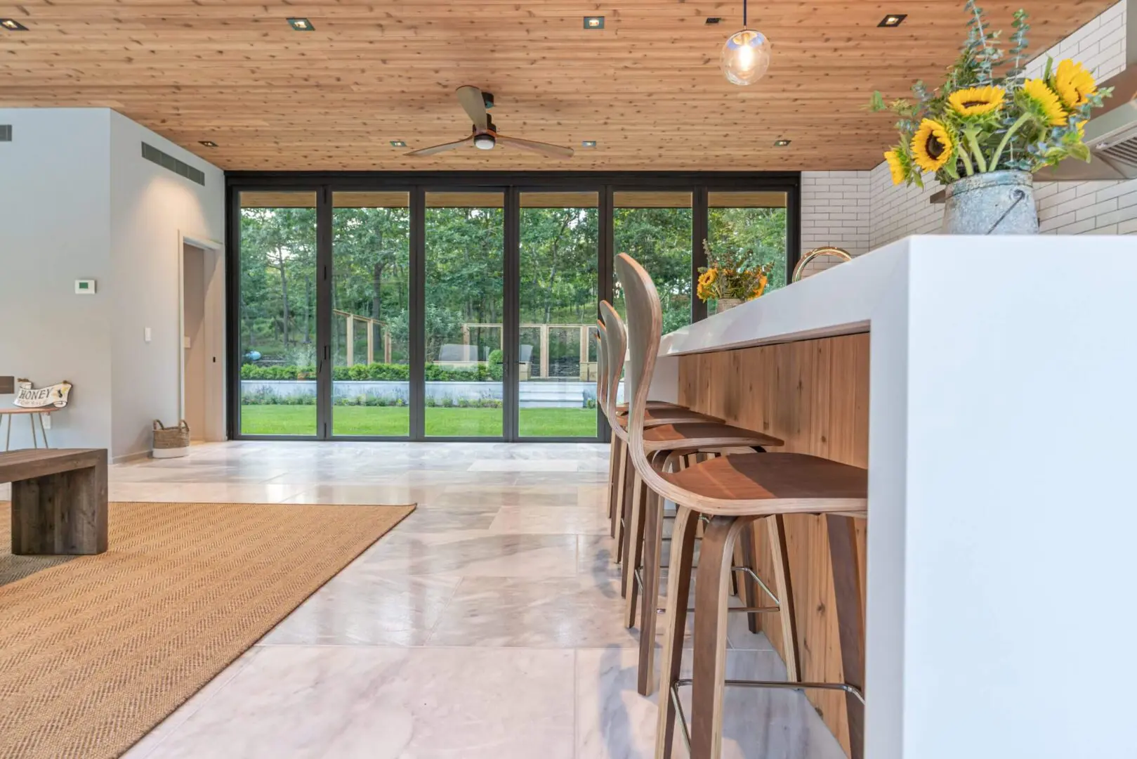 Modern kitchen island with wooden stools and large glass doors.