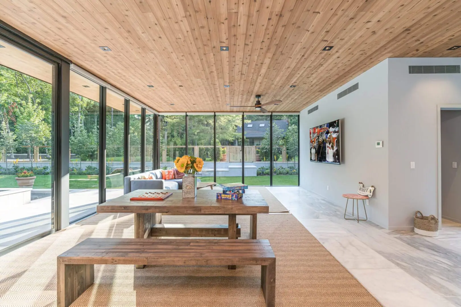 Modern living room with large glass windows and wooden furniture.