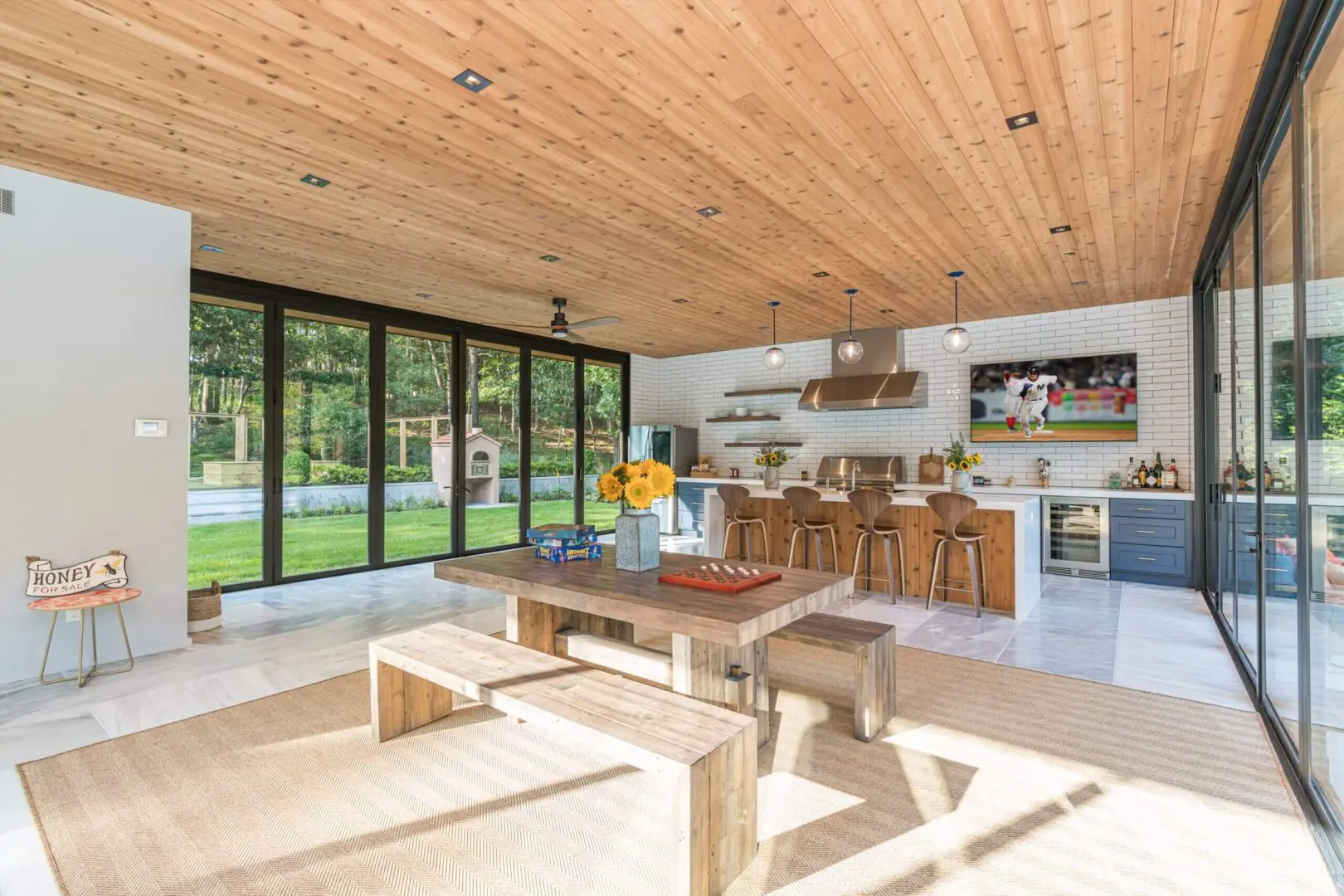 Spacious modern kitchen and dining area with wooden ceiling and large glass doors.