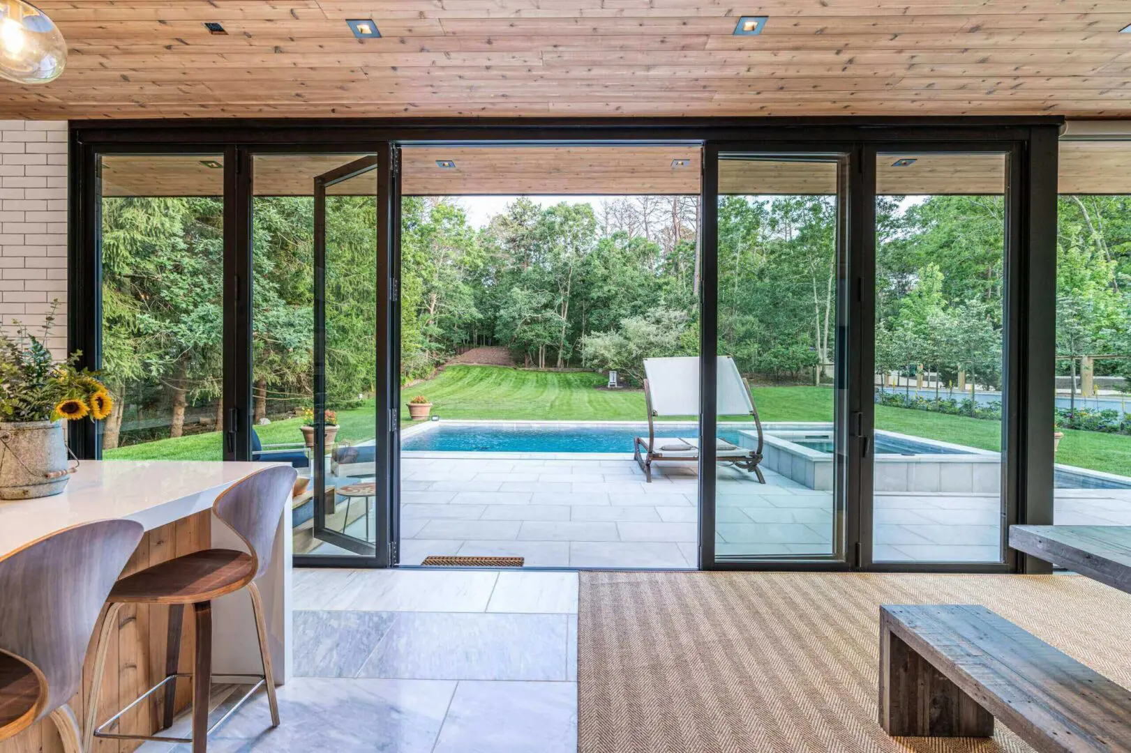 Modern living room with glass doors opening to a backyard pool and greenery.