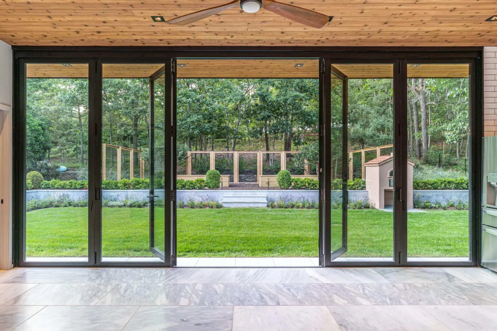 Open glass doors overlooking a backyard with a pool and green lawn.