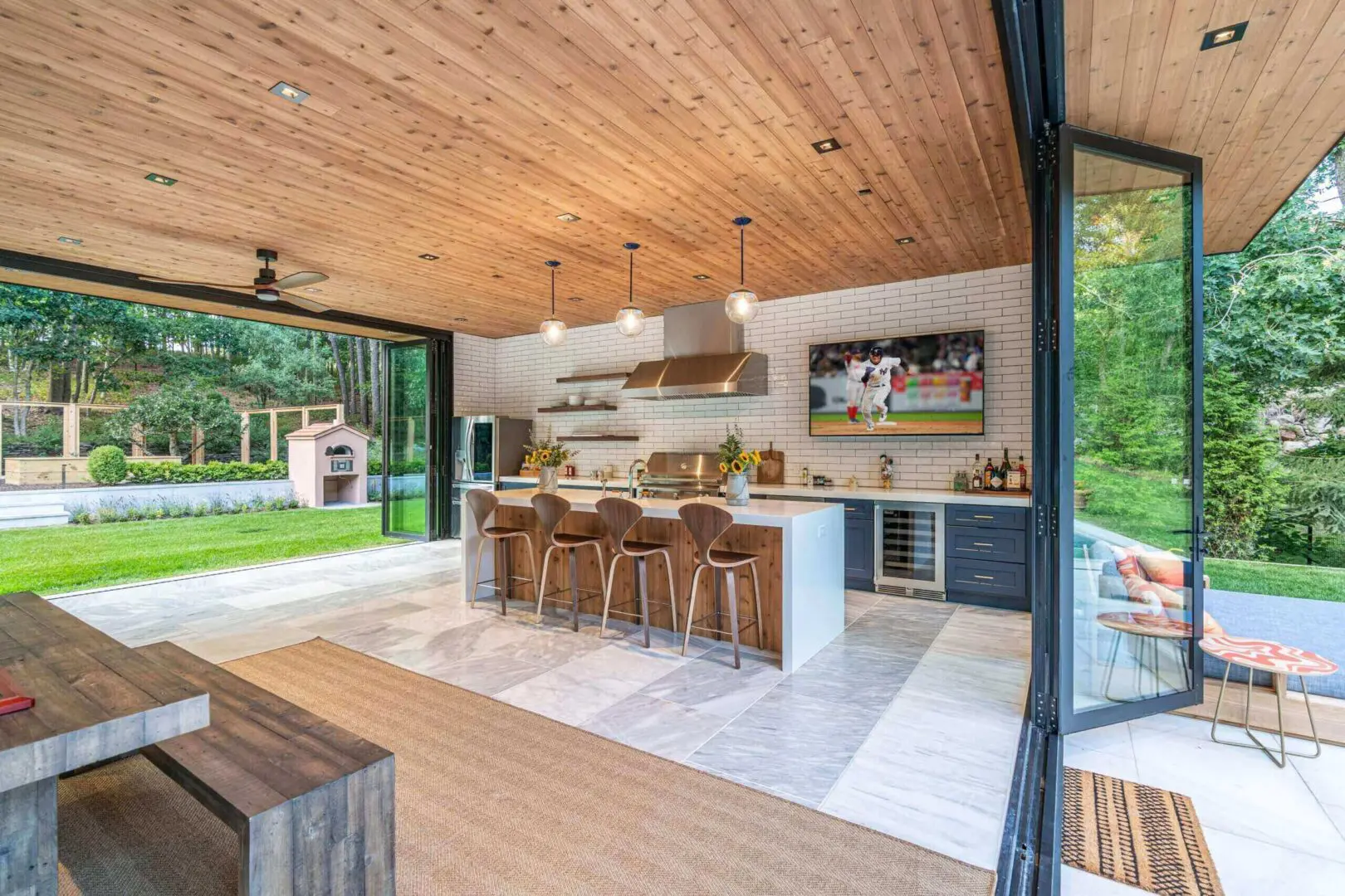 Modern open kitchen with wooden ceiling and outdoor view.