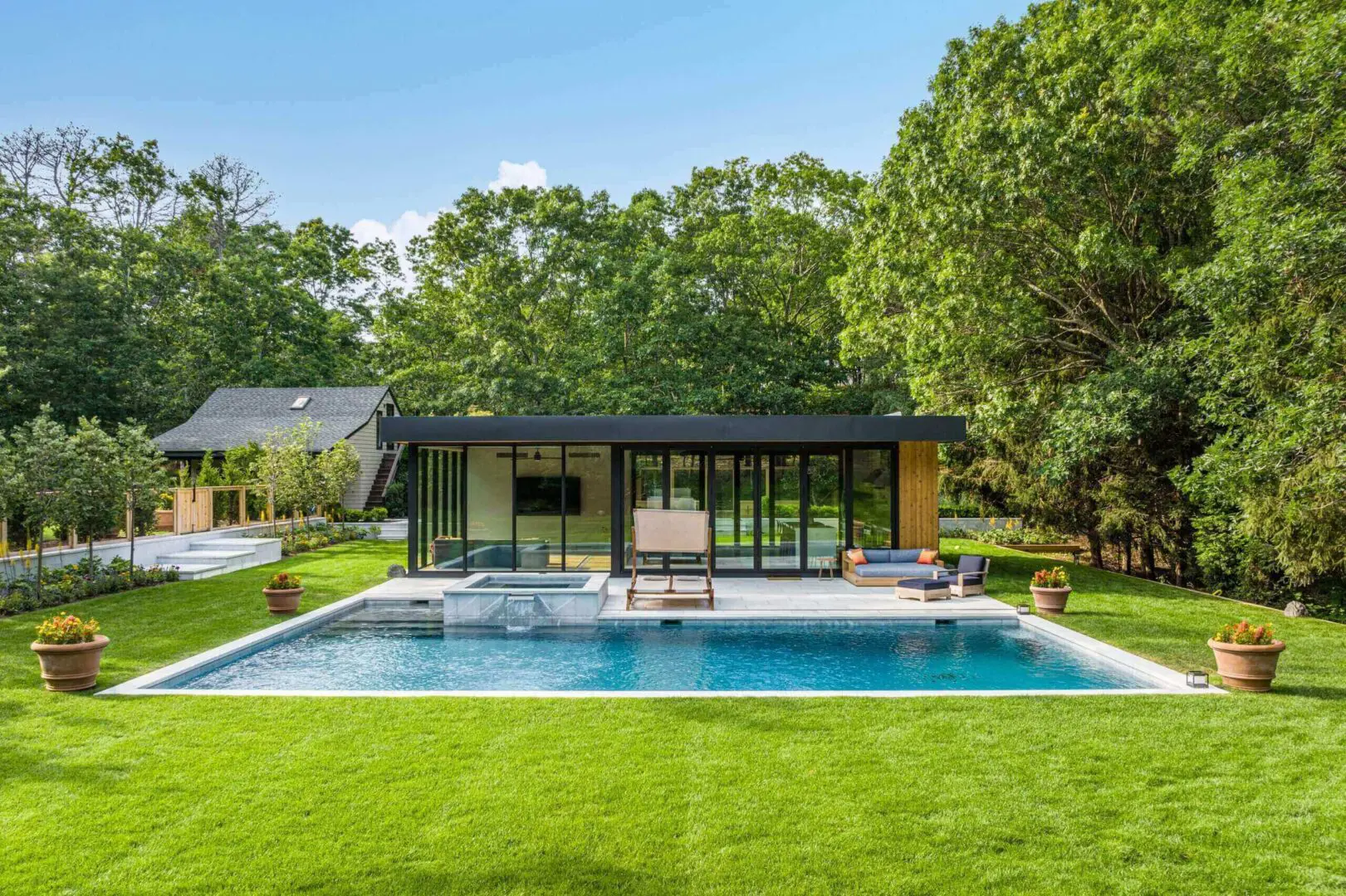 Modern house with a pool and lush green lawn under a clear sky.
