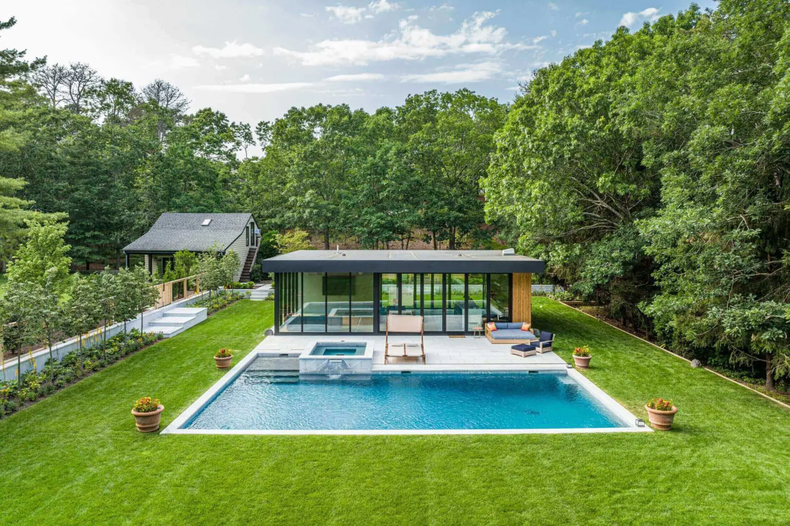 Modern house with a swimming pool surrounded by lush greenery.
