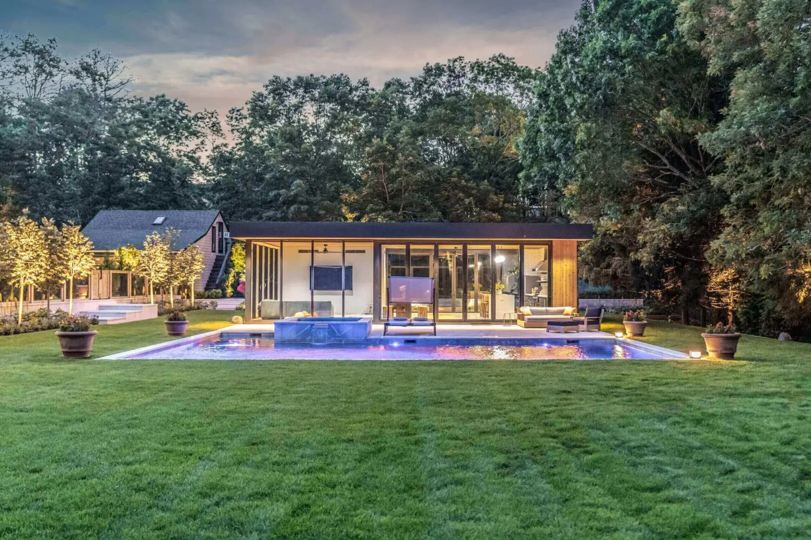 Modern house with a pool and manicured lawn at dusk.