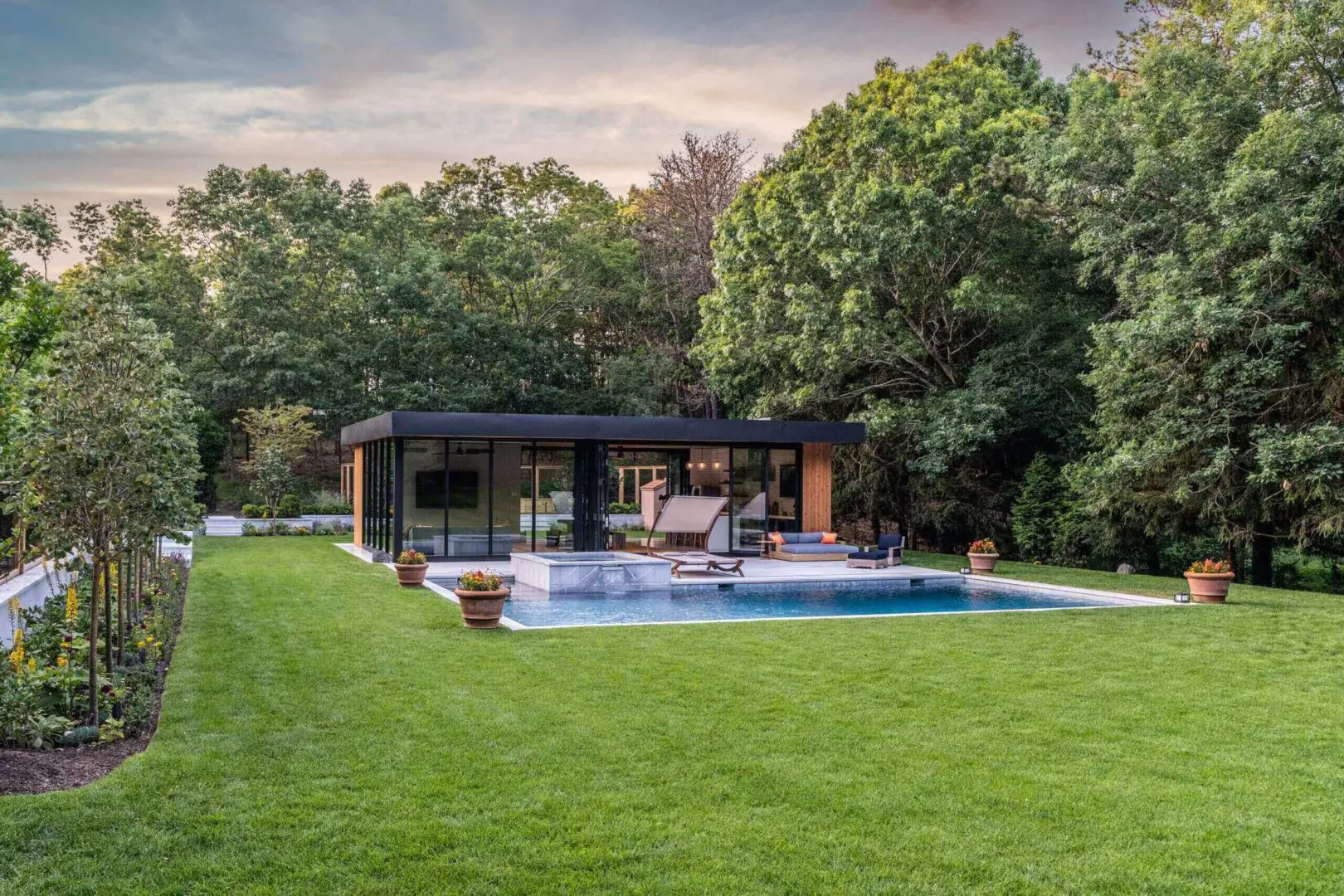 Modern pool house with a swimming pool surrounded by lush greenery.