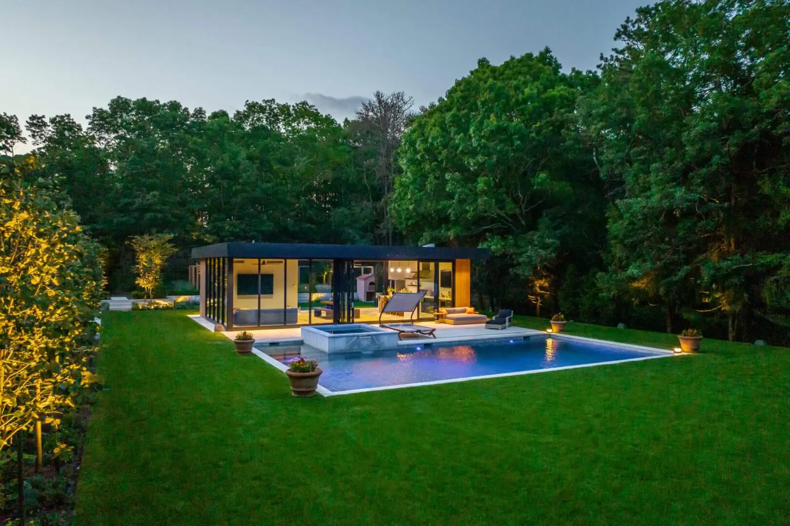 Modern house with large glass windows and a swimming pool at dusk.