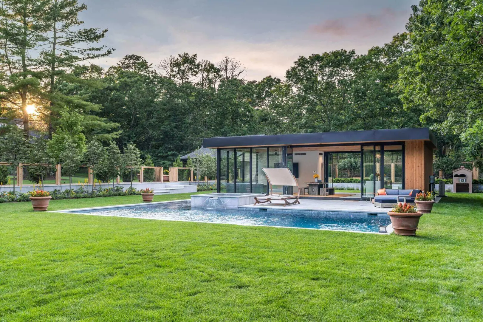 Modern house with a pool and lush green lawn at sunset.