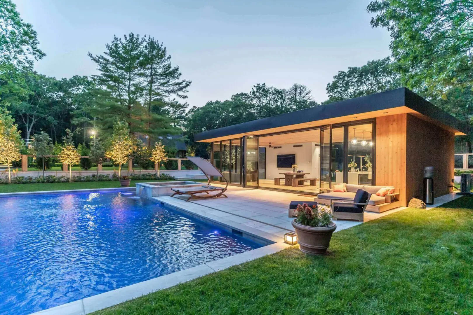 Modern house with illuminated pool and patio at dusk.