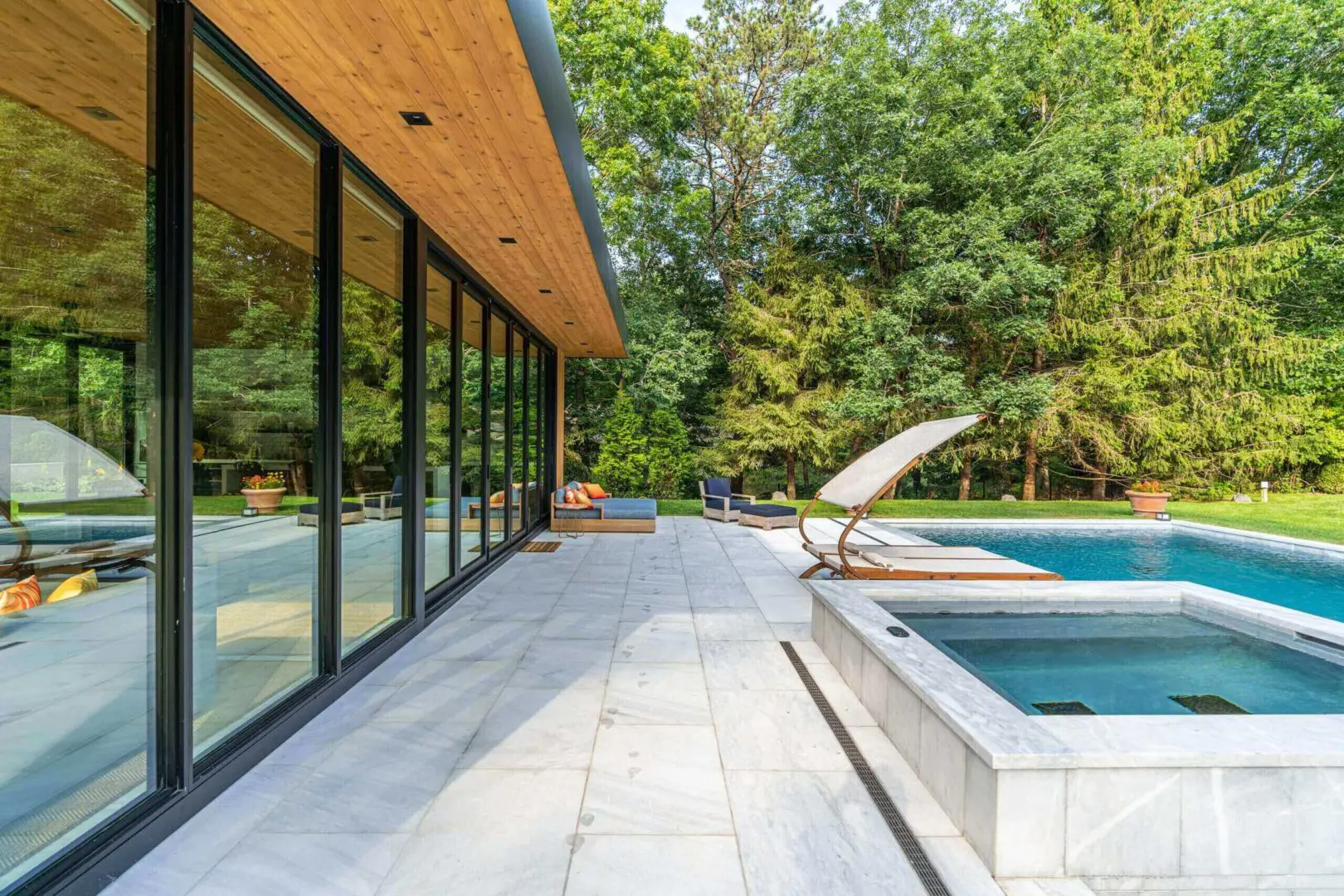 Modern poolside area with lounge chairs and glass building.