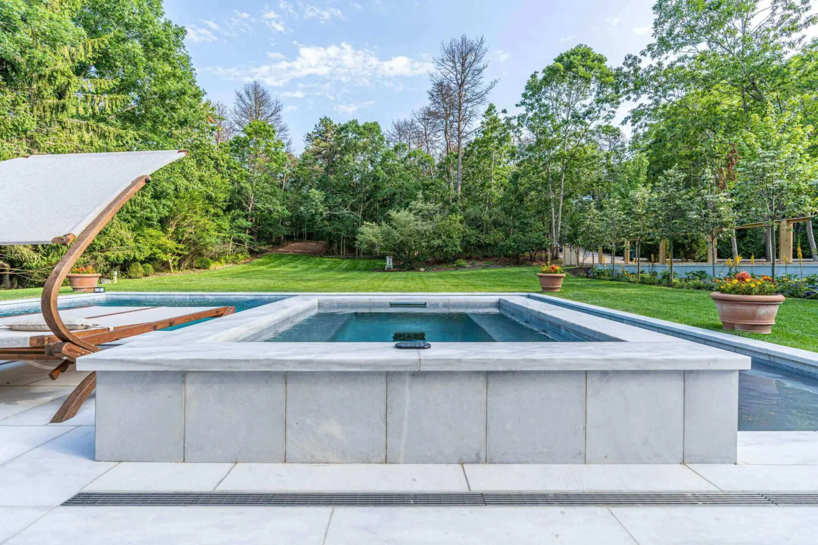 Modern backyard pool with lush green trees surrounding it.