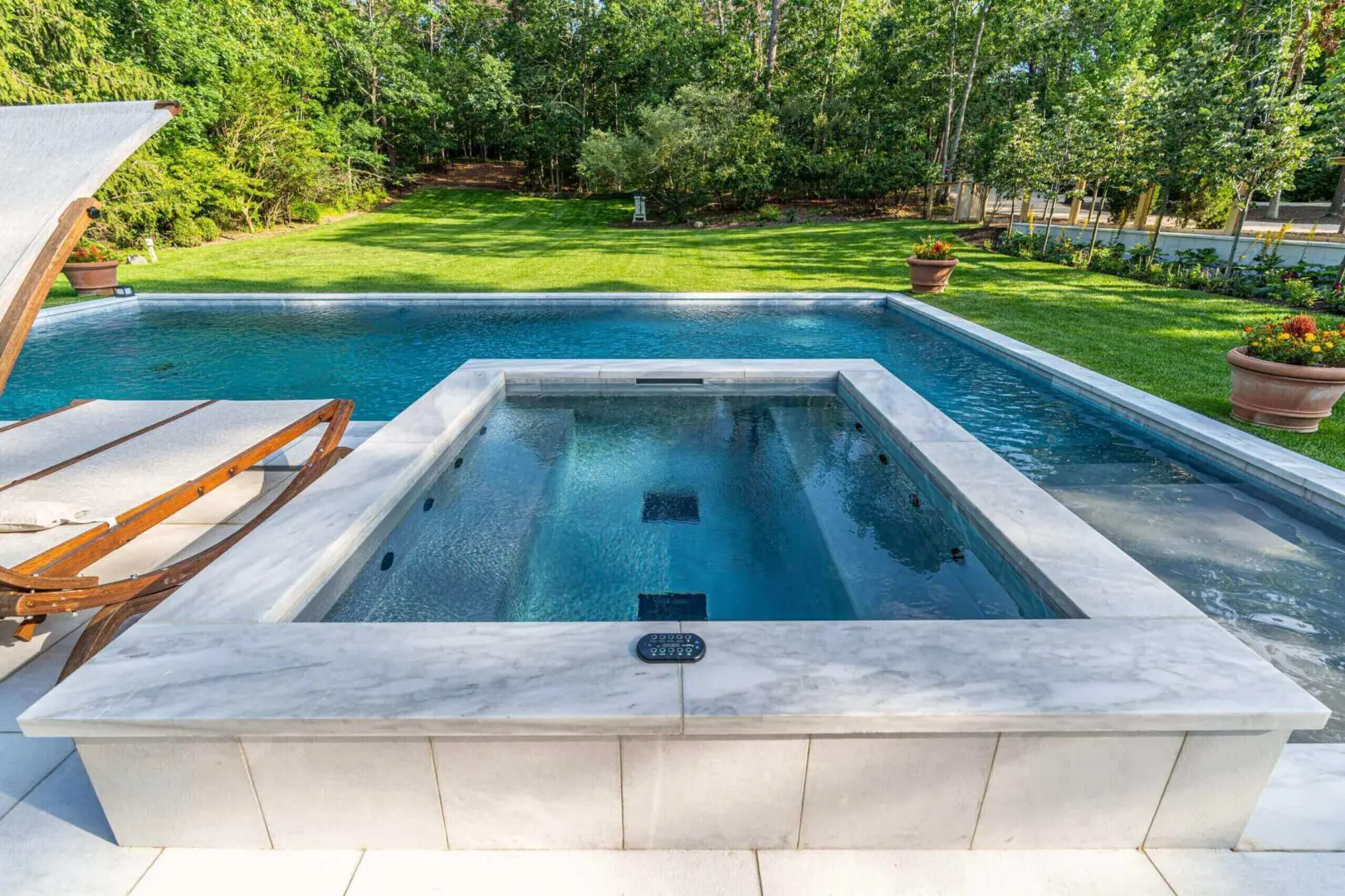 A clean, empty hot tub beside a blue swimming pool in a sunny garden.