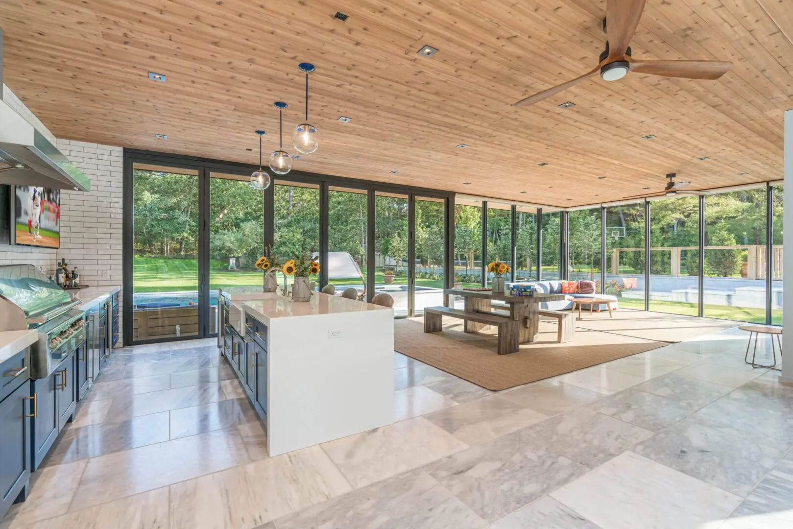 Spacious modern living room with large glass windows and wooden ceiling.