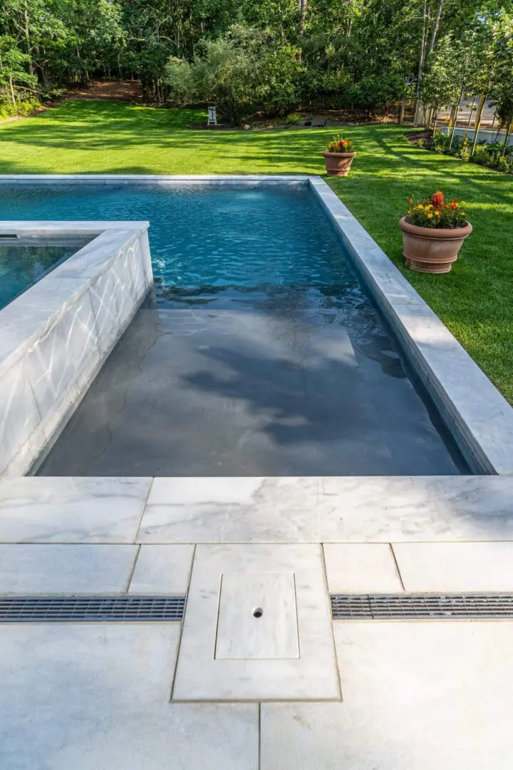 Modern rectangular outdoor pool with clear water and surrounding greenery.