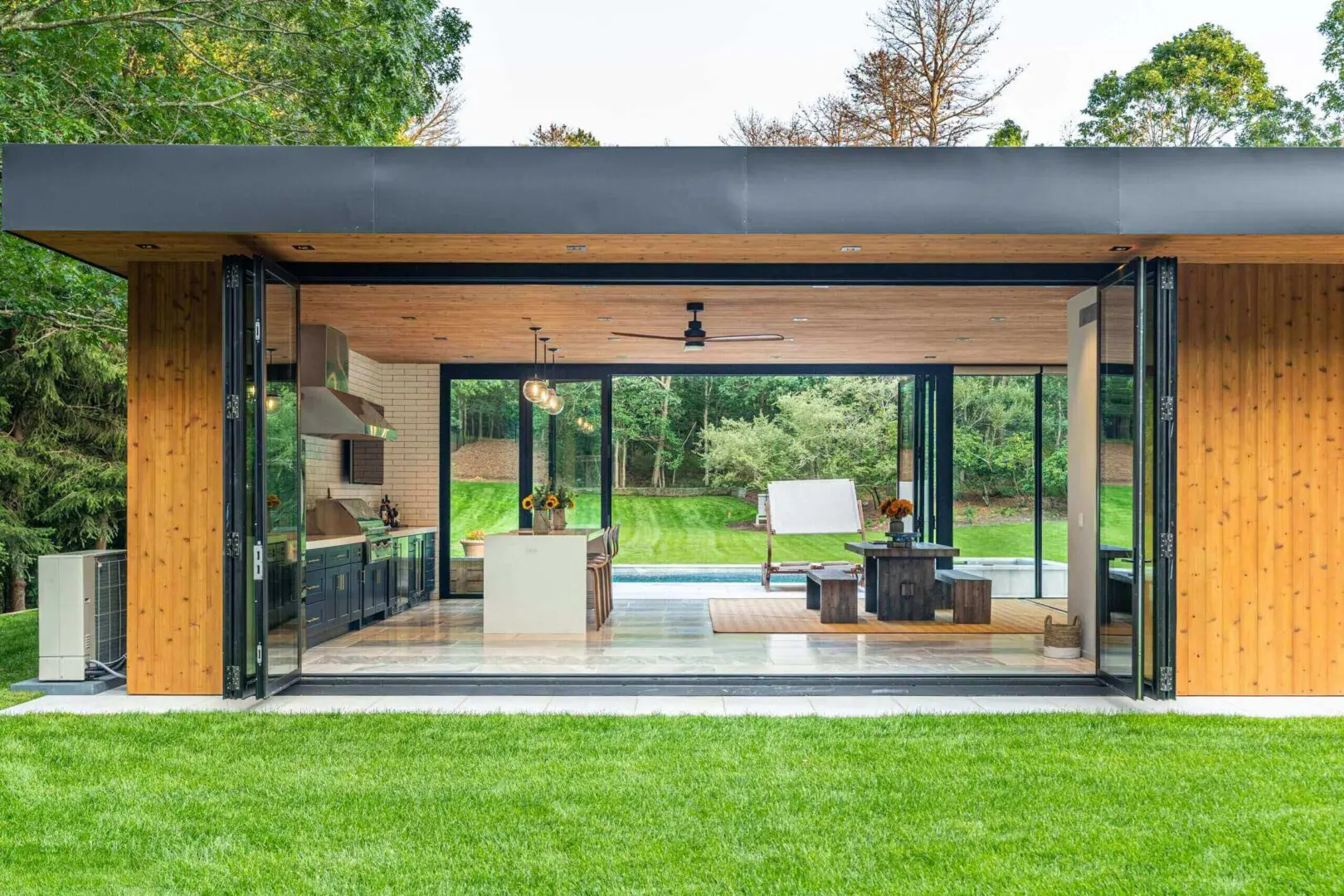 Modern glass-walled living room with green lawn view.