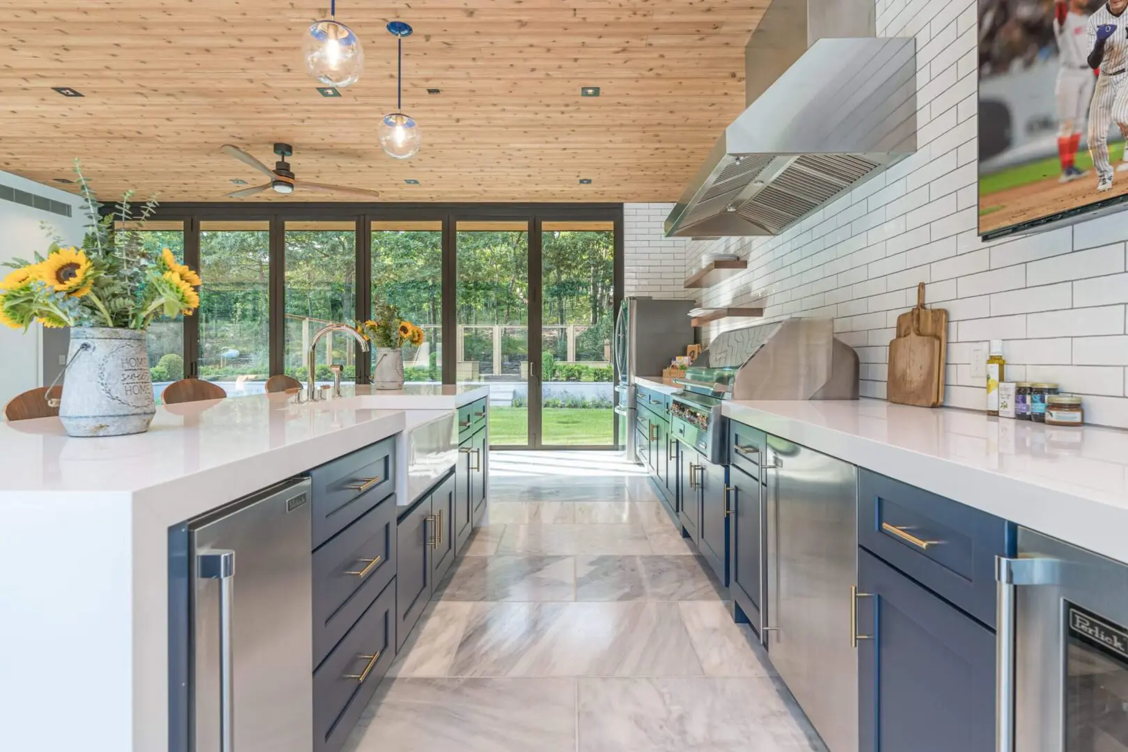Bright modern kitchen with dark cabinetry and large windows overlooking a green backyard.