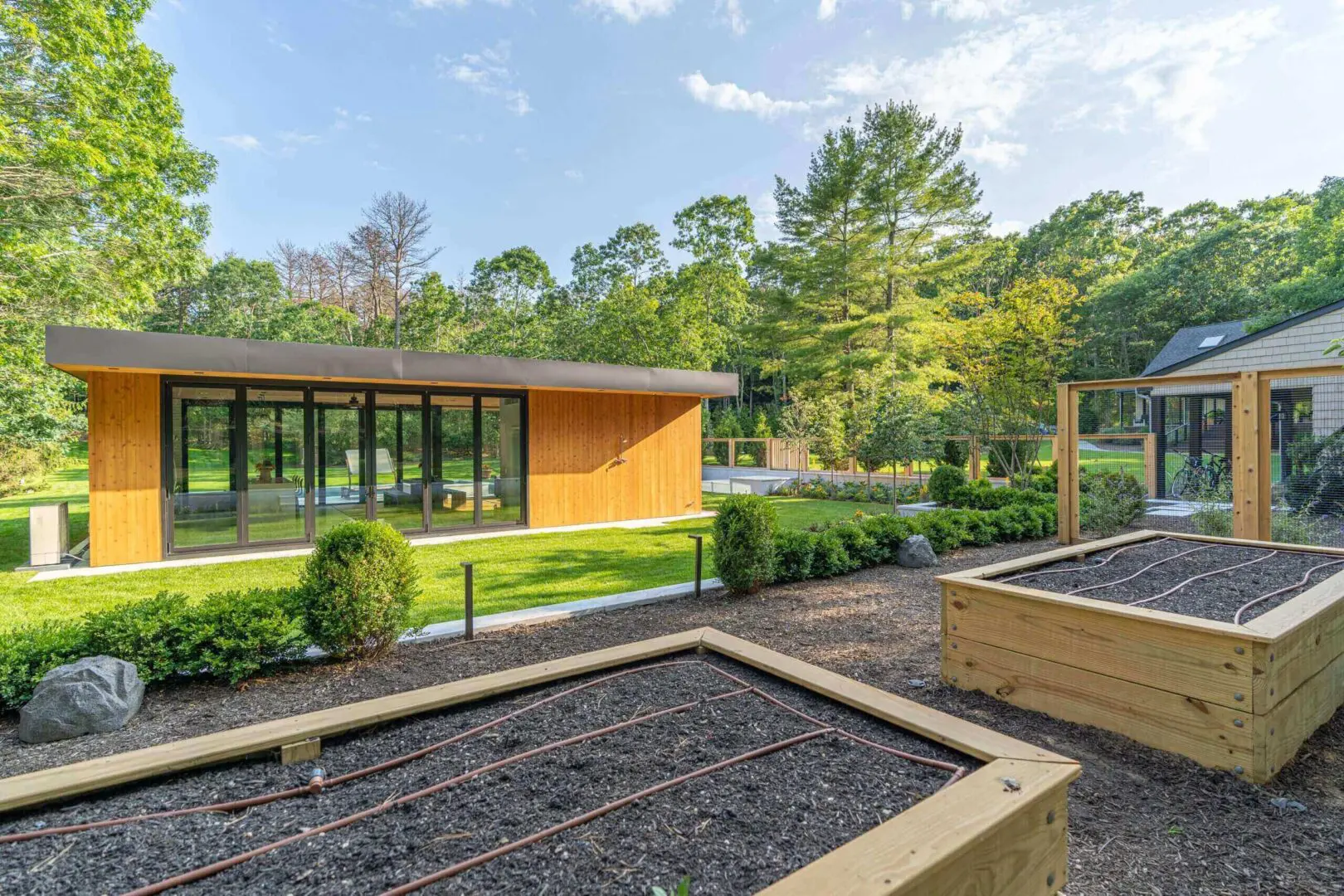 Modern cabin surrounded by lush greenery and raised garden beds.