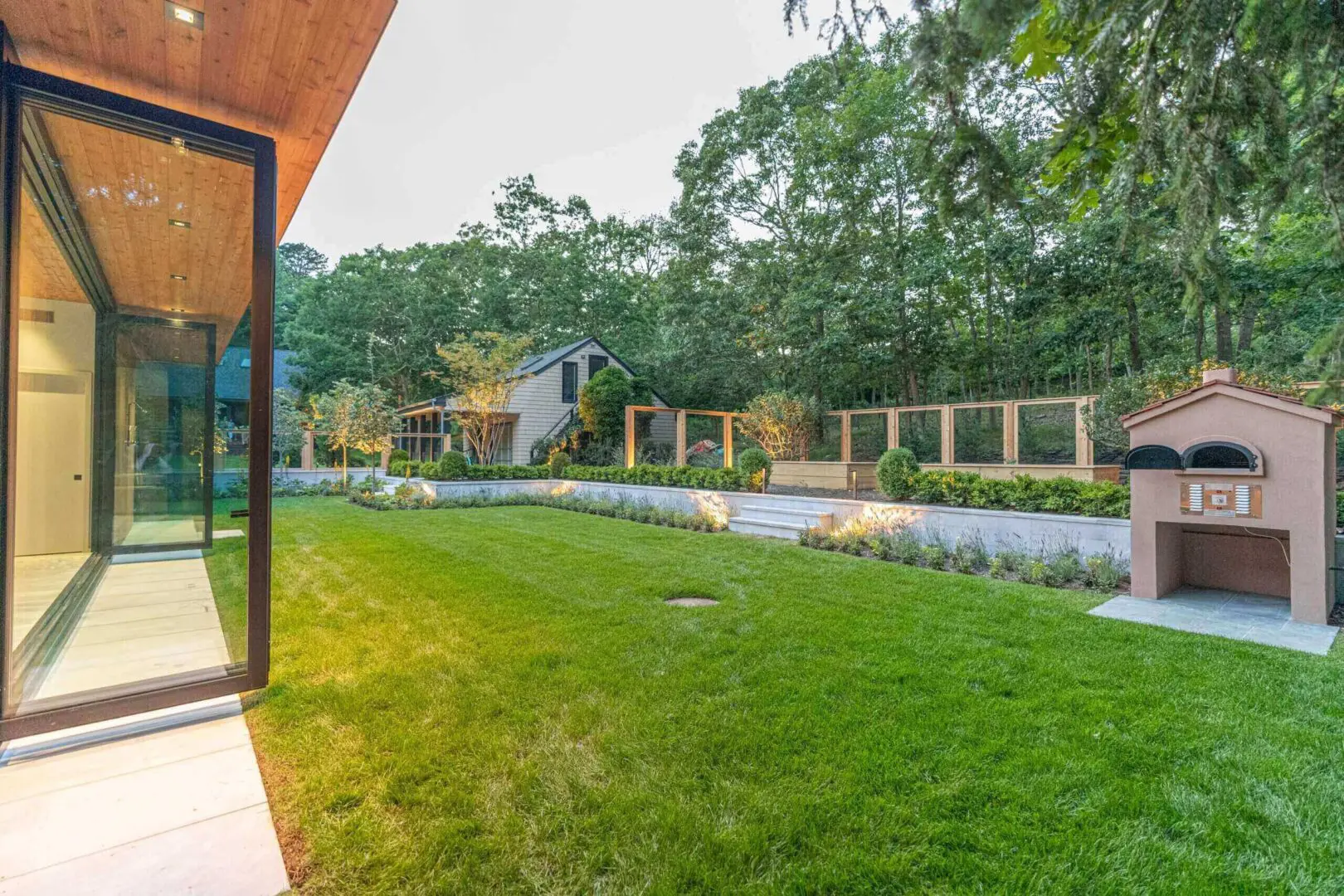 Modern backyard with lush green lawn and wooden fence under cloudy sky.