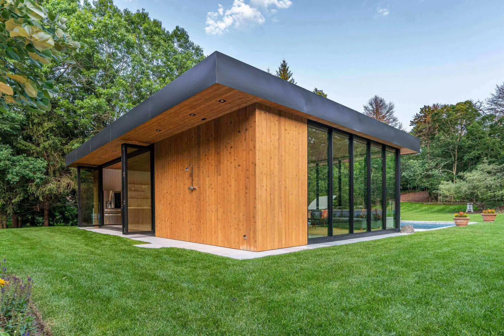 Wood-clad pool house with glass corner walls