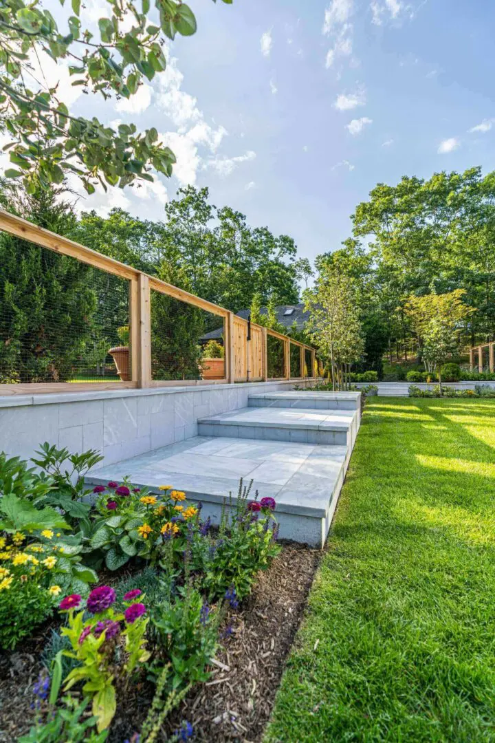 Modern backyard patio with glass railing and green lawn.
