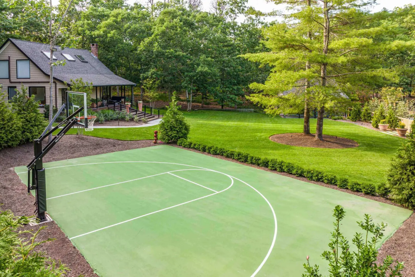 Outdoor basketball court surrounded by greenery and a gazebo.