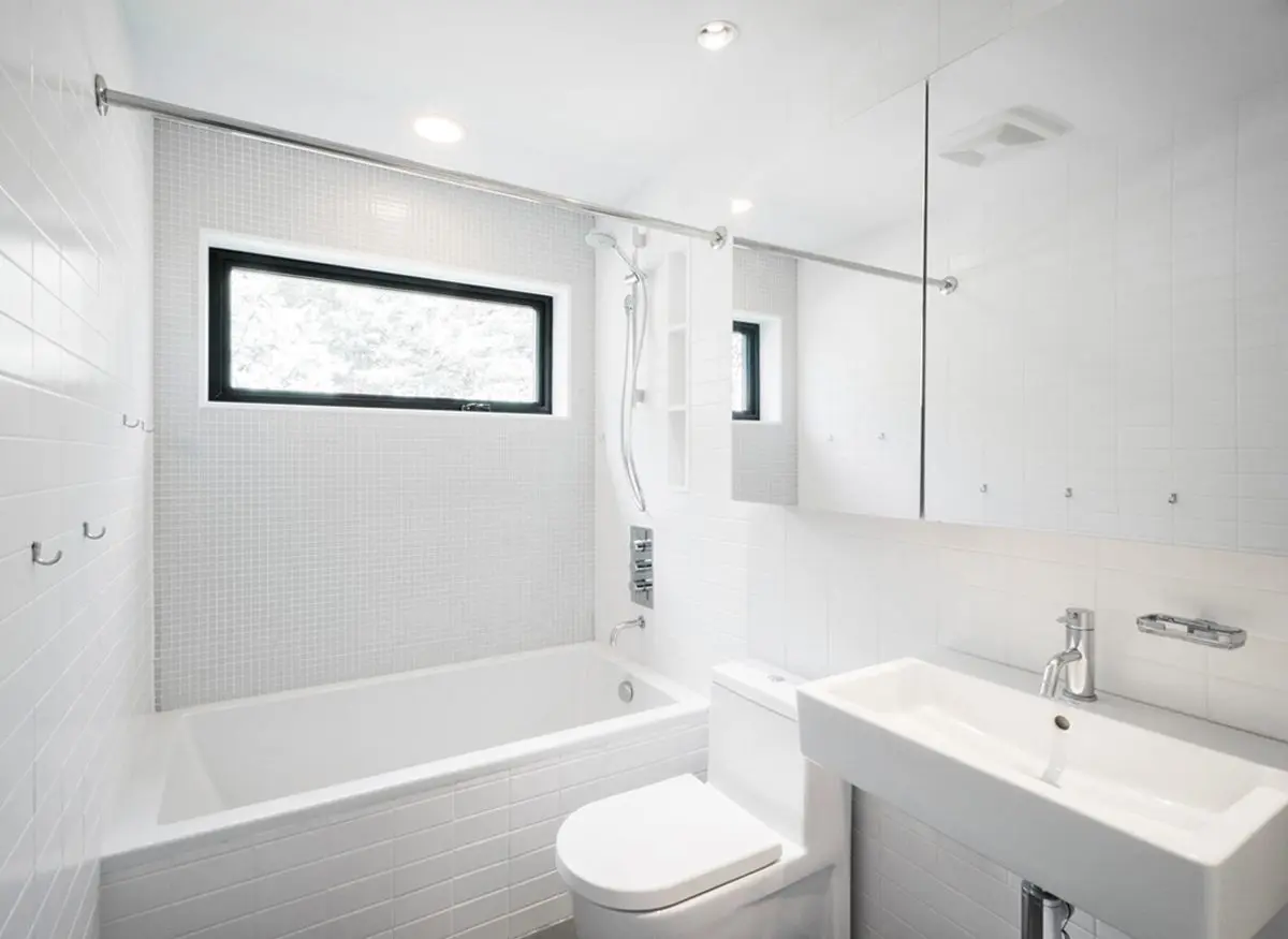 Bright and modern bathroom with white tiles and fixtures.