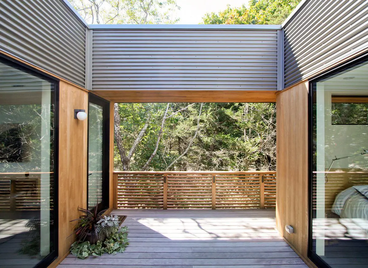 Modern open-air patio with wooden and metal accents overlooking greenery.