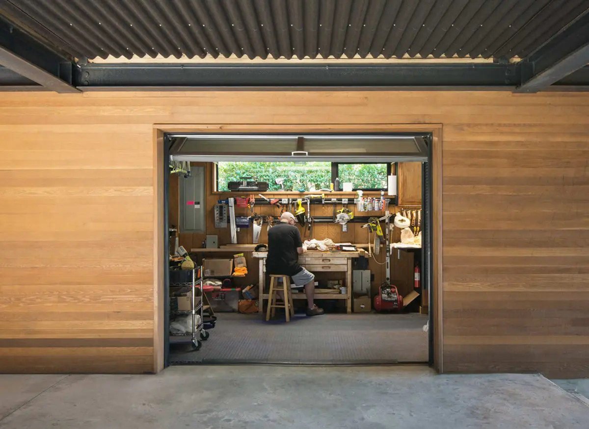 Person working at a cluttered desk inside a wooden workshop.