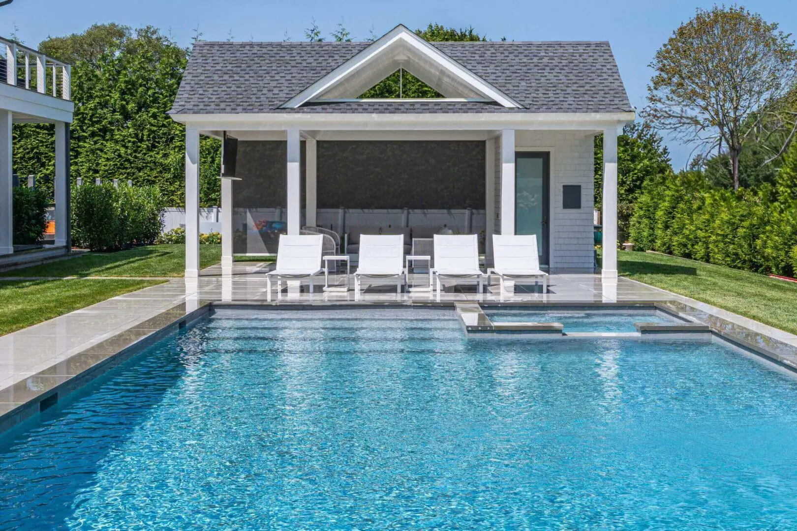 Modern poolside cabana with lounge chairs and clear blue water.