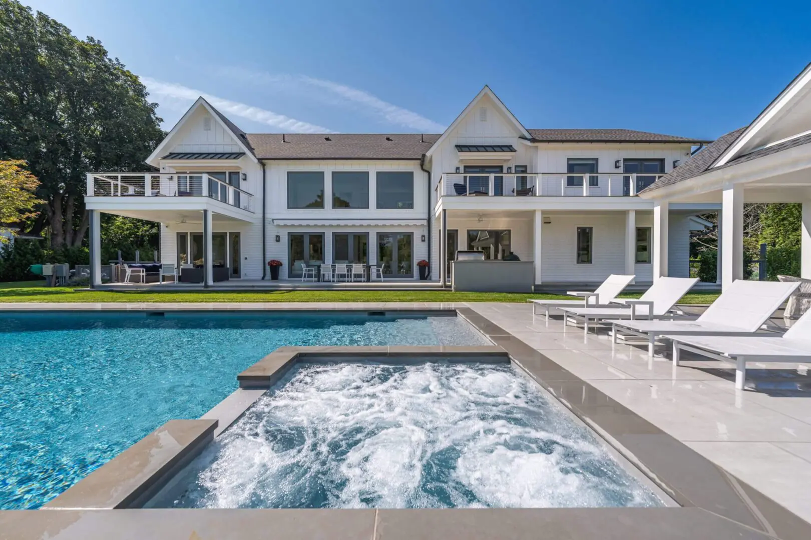 Luxurious modern house with a pool and jacuzzi in the backyard.