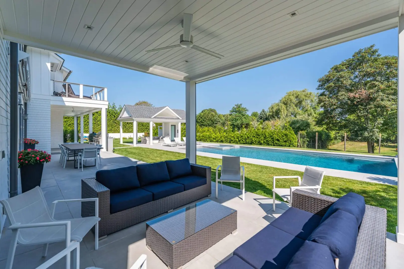 Modern outdoor lounge area with pool and greenery.