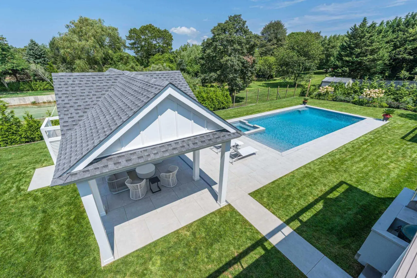 Modern backyard with a swimming pool and outdoor seating area under a covered patio.