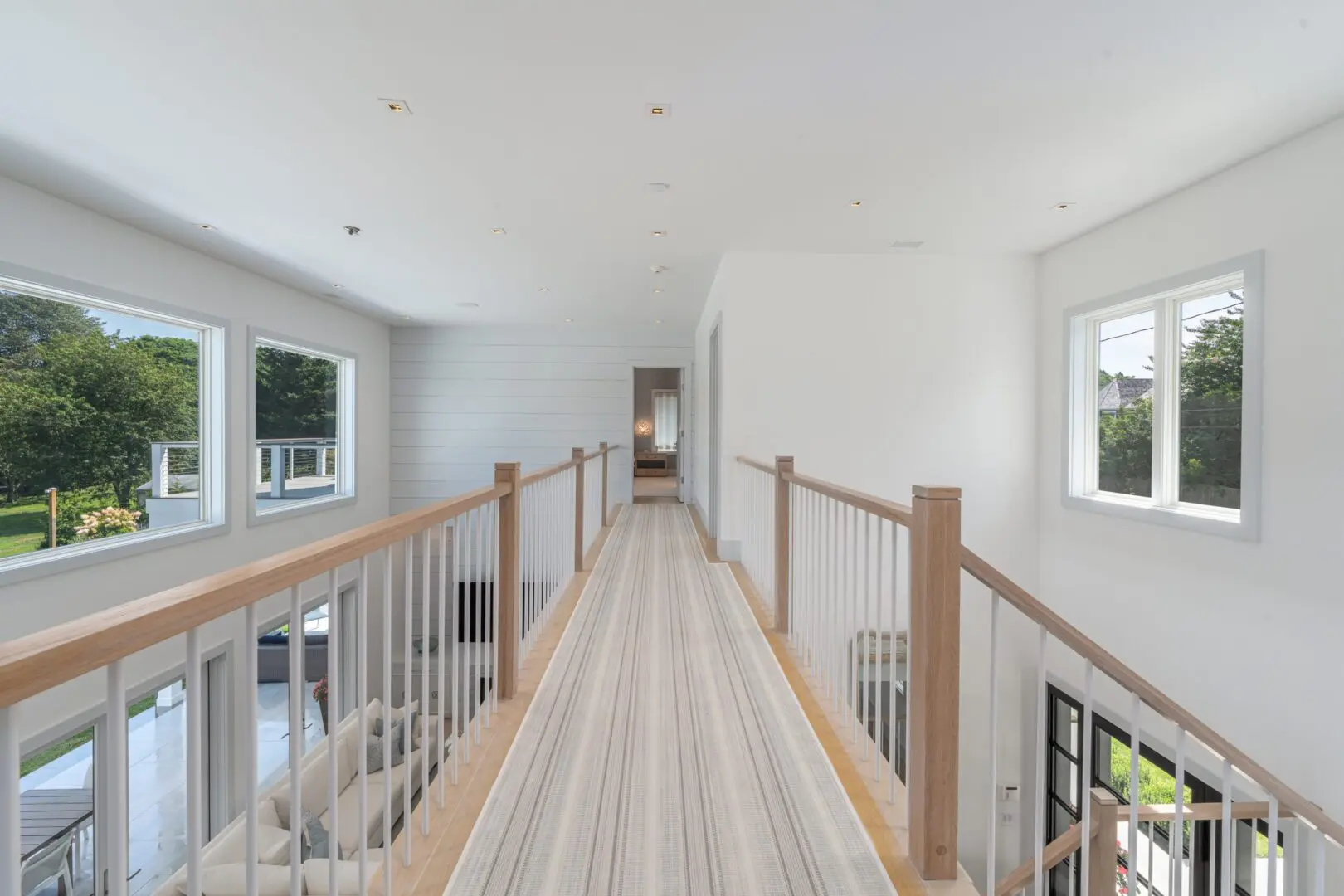 Bright upstairs hallway with carpet runner and wooden railings.