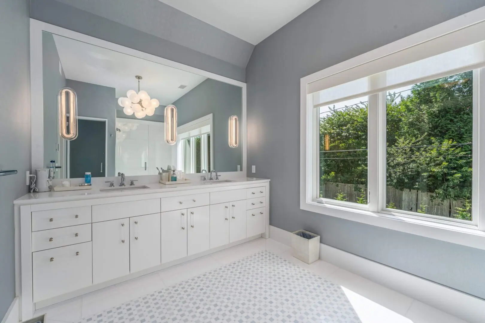 Bright bathroom with white cabinetry and large window.
