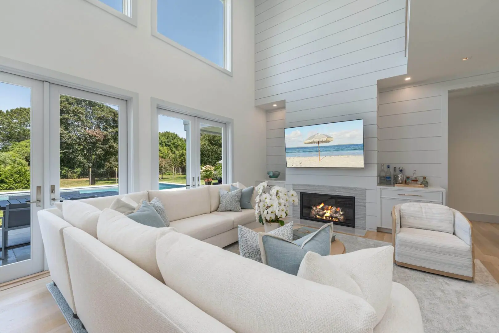 Bright living room with white sectional sofa and fireplace under a TV.