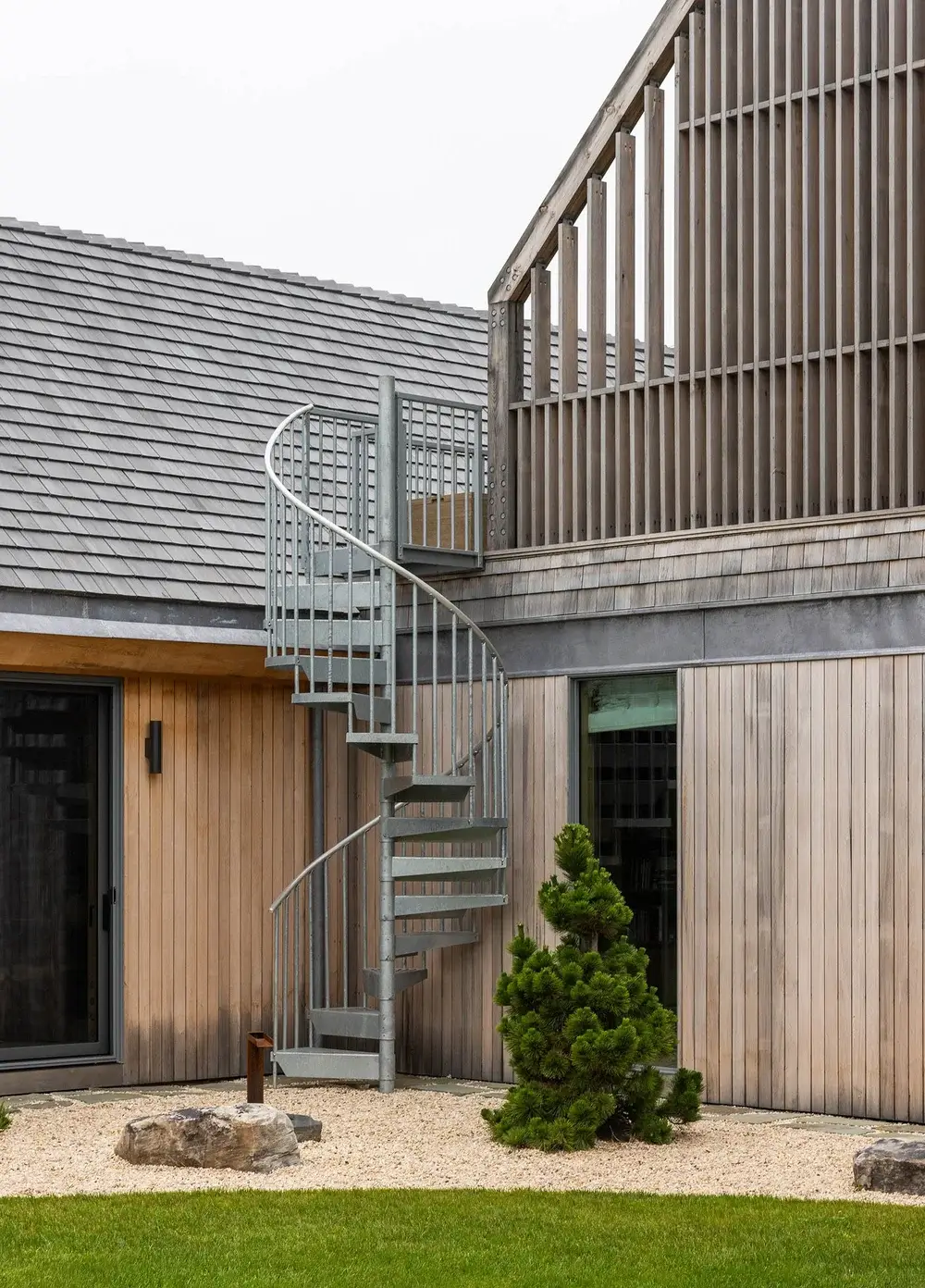 Modern house with a spiral metal staircase and wooden exterior.