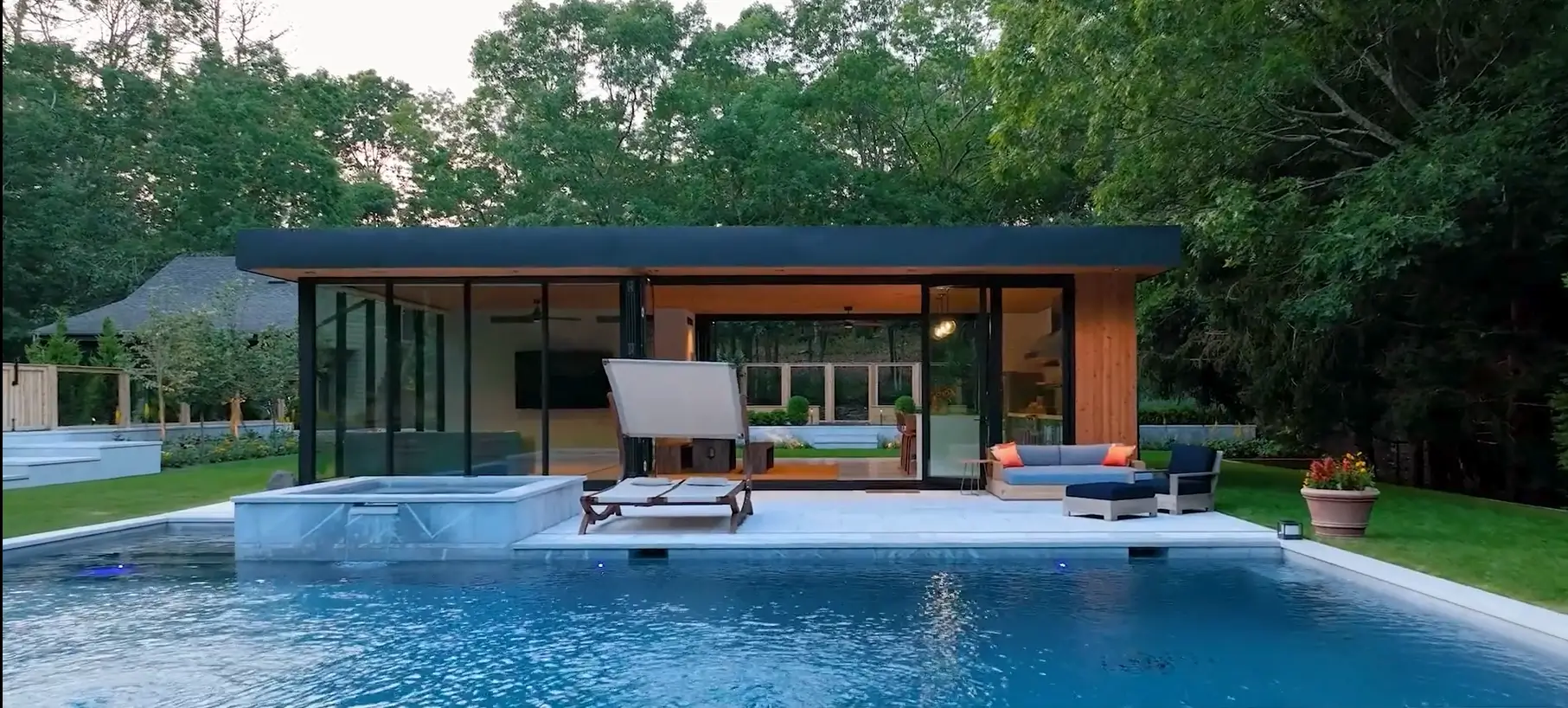Glass-walled pool pavilion with lounge chairs