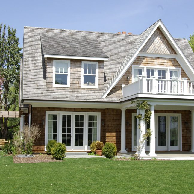 A charming two-story house with a well-kept lawn and clear skies.